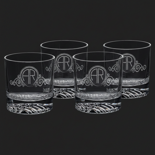 Four custom-engraved 9 oz round rocks glasses with an ornate monogram design (AR) on a dark background