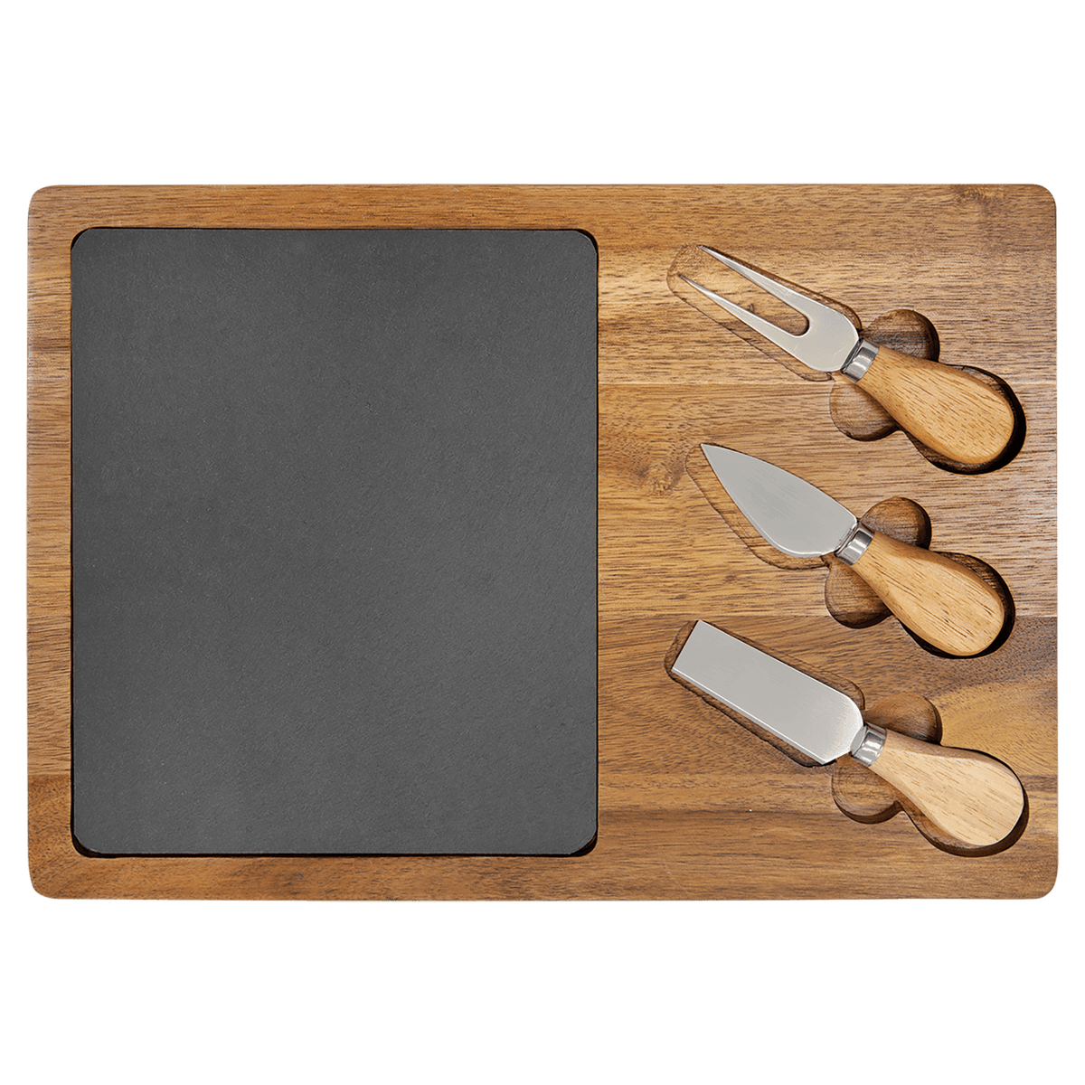 A rectangular acacia wood charcuterie board with a natural wood grain border and a plain slate center. Three stainless steel cheese tools with wooden handles are slotted into the board on the right side.