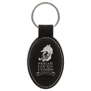 Black leatherette keychain with an engraved silver logo of the silhouette of a man with a beard and pipe, and text "Shear Locks Combs" on a transparent background