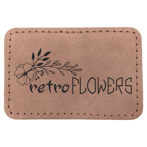 A rectangular blush pink leatherette patch with rounded corners and stitched edges, featuring a black laser-engraved floral illustration and the text 'retro FLOWERS'.