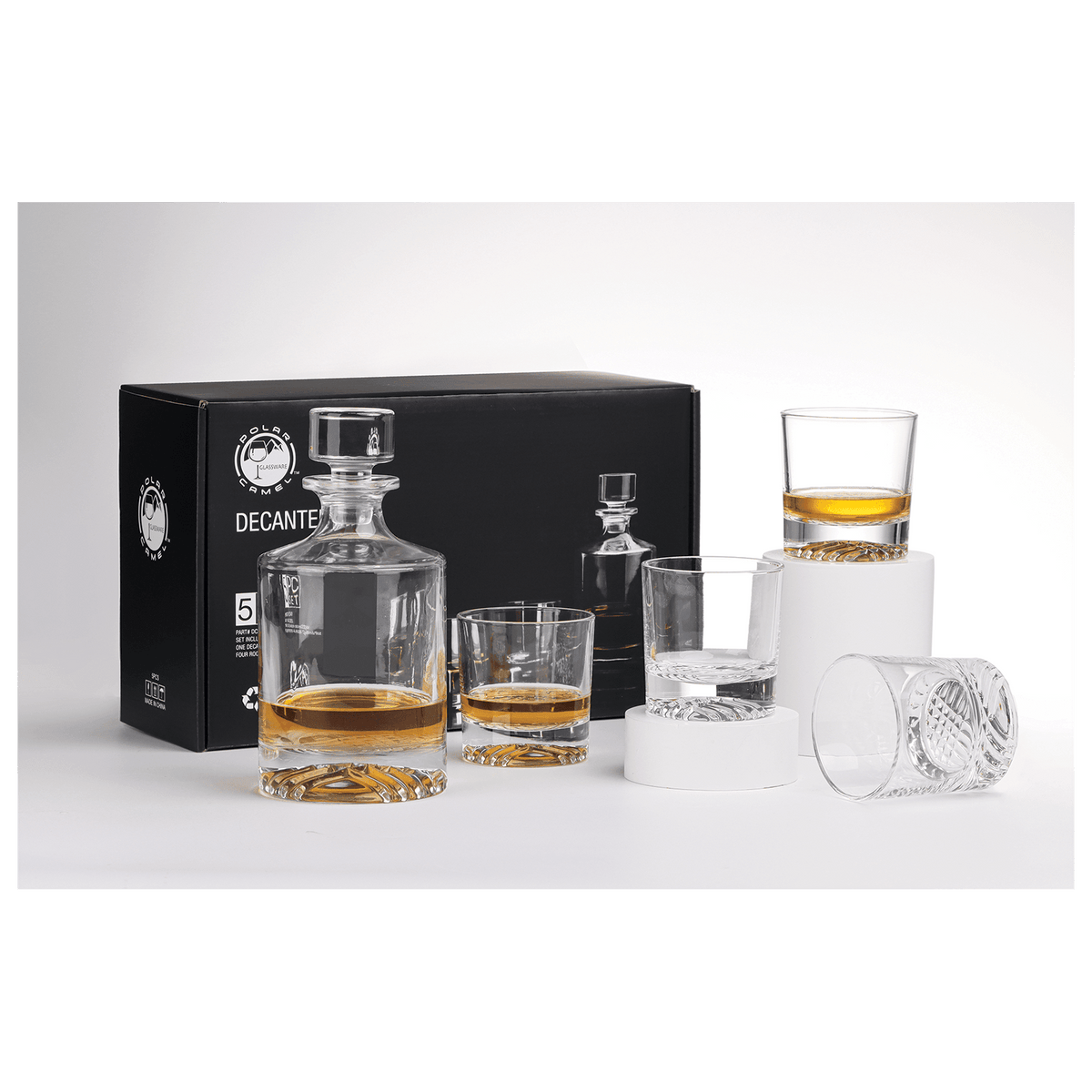 Clear glass round decanter and four matching rocks glasses with amber liquid and custom laser etching, displayed in front of an open black gift box on a white surface