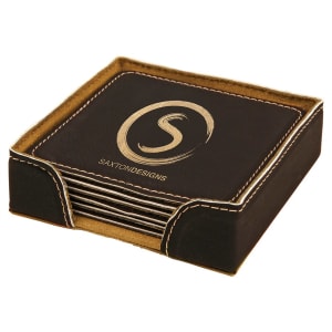 A black and gold leatherette coaster set with a matching holder, featuring a 'Saxton Designs' logo laser-engraved in the center.