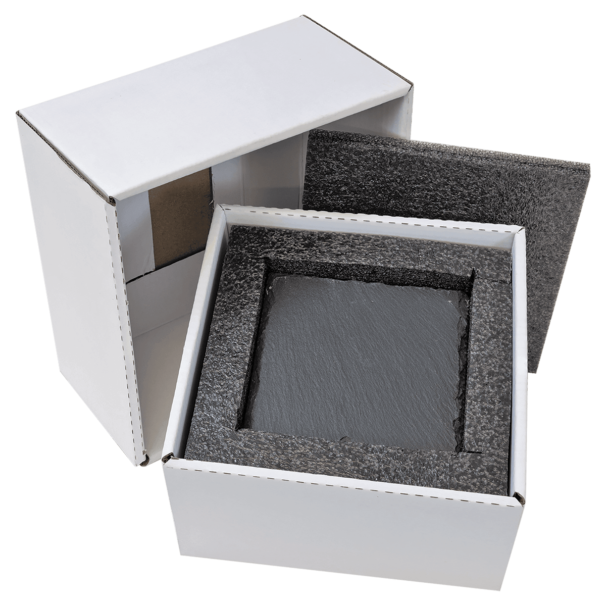 A white shipping box sits open with its lid resting beside it, revealing a square slate coaster nested securely inside dark, protective foam packaging. The slate coaster is ready to be personalized with custom engraving.
