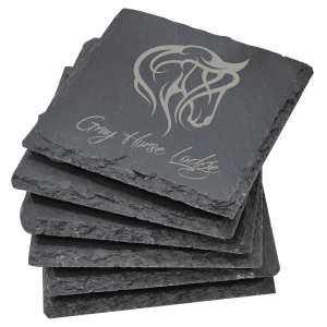 "A stack of six square, black slate coasters, with natural hand-chiseled edges and a custom 'Grey Horse Lodge' logo laser-engraved on the top coaster.